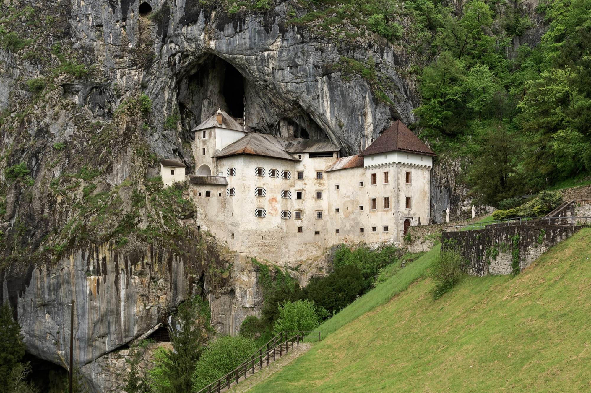 The white walls of Predjama Castle under the overhanging cave arch